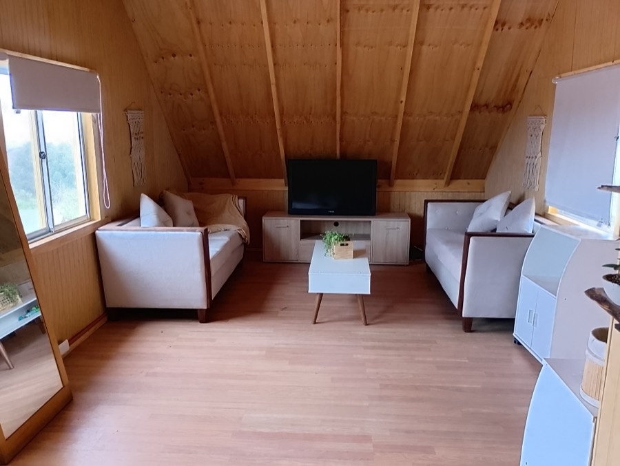 Estar interior forrado en madera con sillones blancos