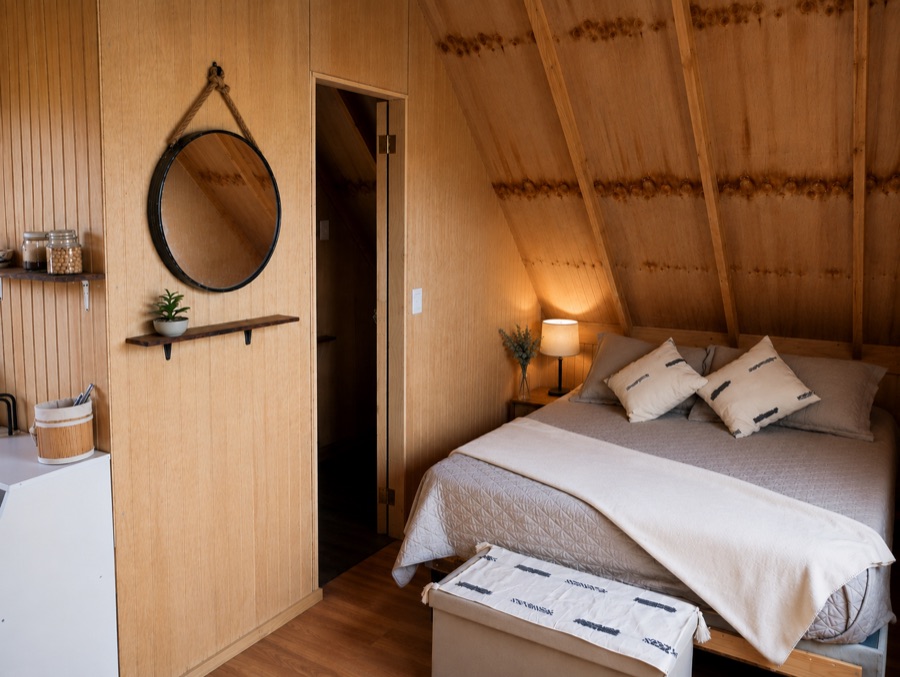 La habitación forrada en madera, con cama de dos plazas y luz cálida
