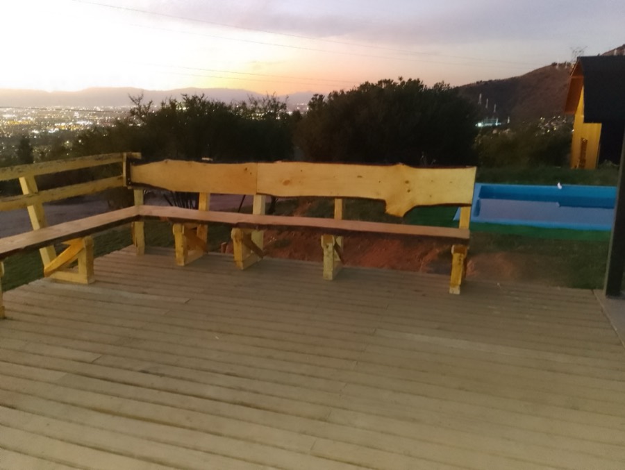 Deck de madera con bancas de tablón de canto vivo, mirando hacia la ciudad al atardecer