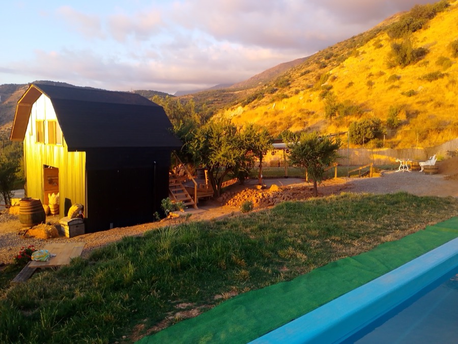 Ladera del cerro dorada por el sol de la tarde, con la piscina abajo