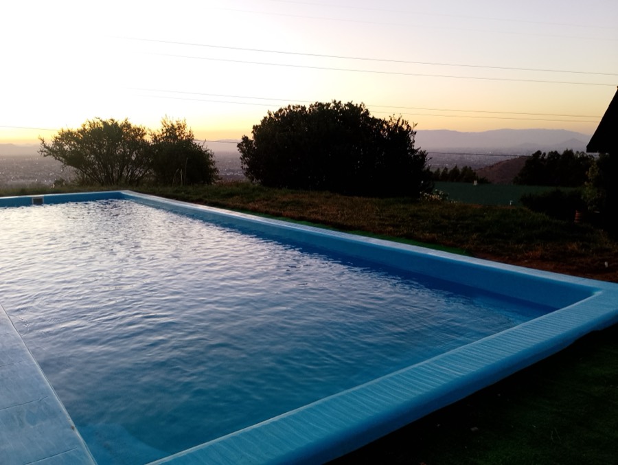 Piscina alargada reflejando el cielo del atardecer, rodeada de pasto